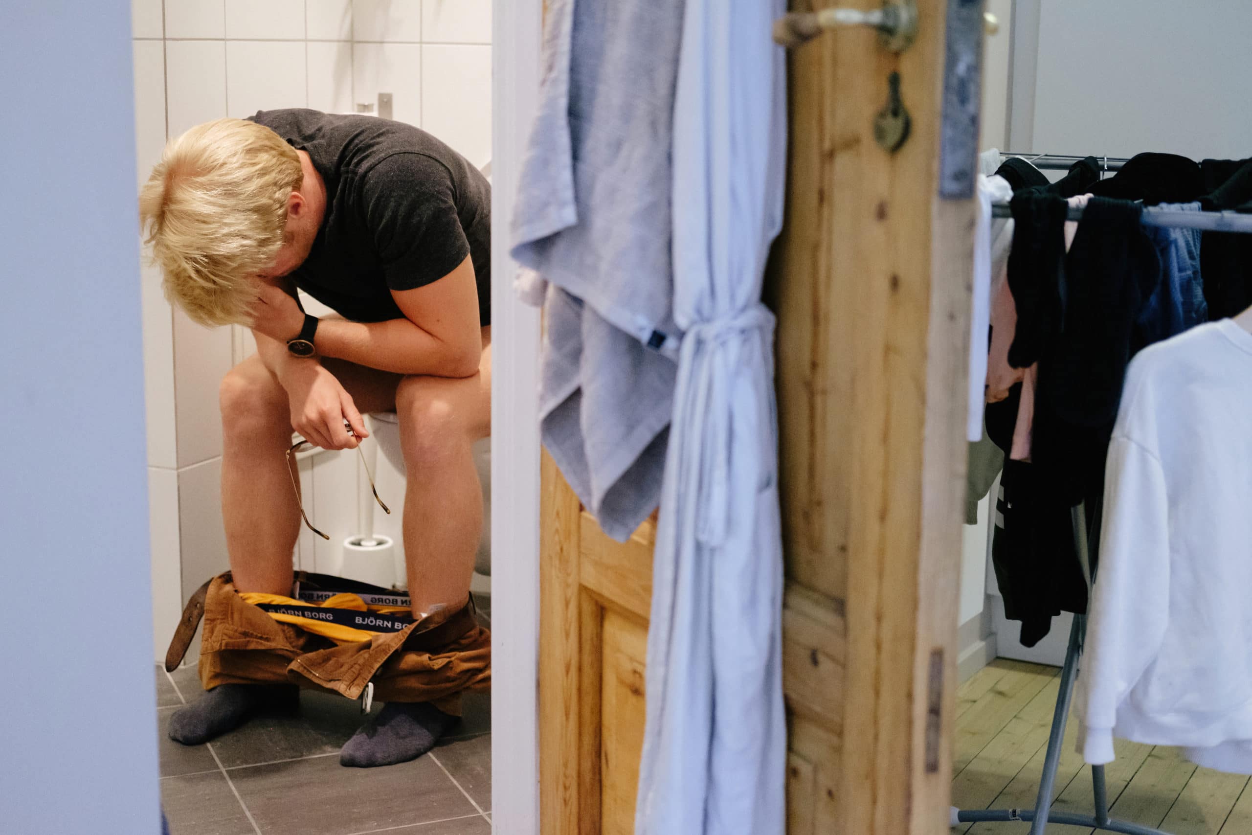 Mann sitter foroverbøyd på do. Luft i magen?